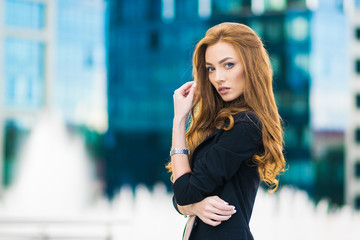 Fototapeta premium Happy woman standing outdoors in business casual suite against modern mall