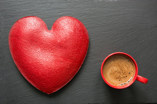 Valentines day composition with red coffee cup and big heart of red velvet cake over slate plate. Top view. Copy space.