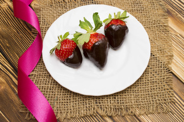 Fresh strawberries dipped in dark chocolate and heart on wooden background. Valentine's Day