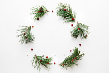 Traditional Christmas wreath made from pine branches and red berries on a white background. Flat lay, top view.