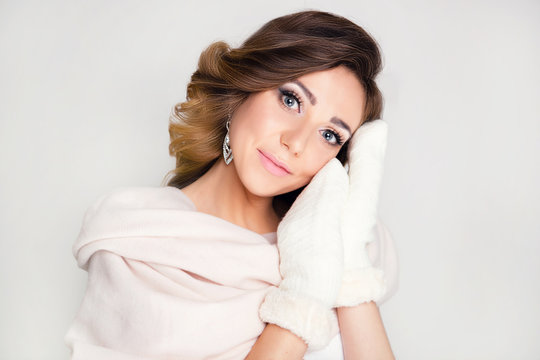 Beautiful woman in winter image. Professional make-up and curls, white gloves and a pink scarf. Eyelash extension, New Year discounts.