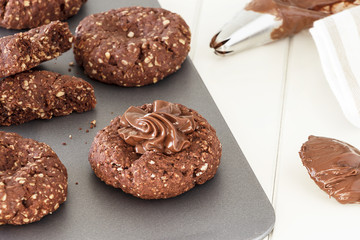 Process of cooking chocolate oatmeal cookies. Cream decoration oats cookies. Selective focus. Close up.