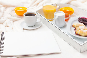 Freshly baked croissant, orange juice, jam, cup of black coffee on white wooden tray on plaid. Homemade cookie. Fresh pastries for breakfast. Delicious dessert. Closeup photography. Horizontal banner