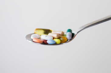 different pills and capsules of drugs on spoon