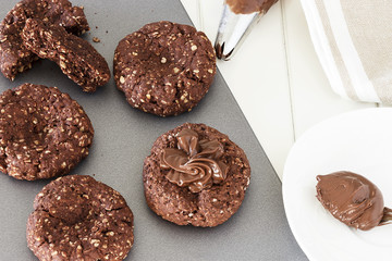 Process of cooking chocolate oatmeal cookies. Cream decoration oats cookies. Selective focus. Close up. Top view.