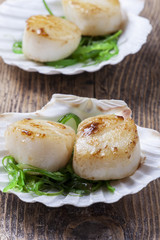 Gegrillte Jakobsmuscheln in Muscheln auf Holz