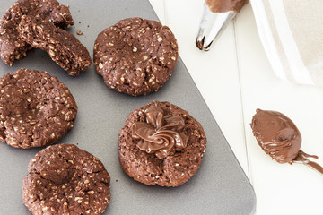 Process of cooking chocolate oatmeal cookies. Cream decoration oats cookies. Selective focus. Close up. Top view.