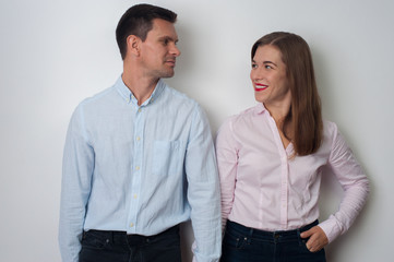 Portrait of loving middle aged couple - attractive man and woman looking at each other and smiling in casual clothes on white background