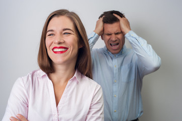 Positive narcissistic beautiful smiling woman stands on the background of an angry crazy man on white background