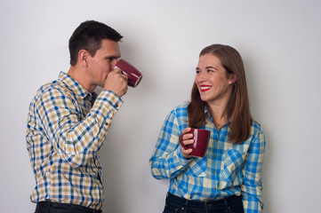 Young couple. Hipsters - positive woman and charming man drinking coffee in checkered shirts on white background