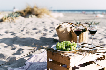 Wineglasses and white grape on beach