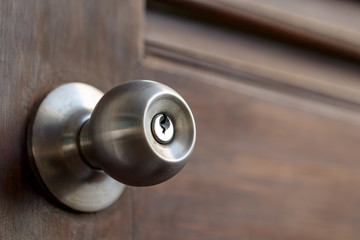 stainless door knob and keyhole on old wooden door, shallow depth of field - obrazy, fototapety, plakaty