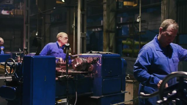 Industrial employees working on automatic turning lathe and metalworking machine