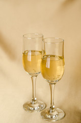 two glasses of champagne on a background of a fabric of golden color. vertical view.