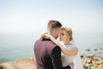 Wedding couple stands on the cliff before the sea