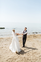 Fototapeta na wymiar Stunning wedding couple has fun on the sea shore