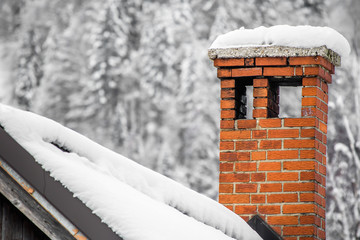 close up on red brick chimney in winter scenery with snow on a rooftop