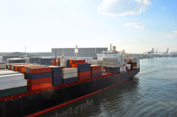 Naklejka premium Part of large merchant ship container vessel in coastal waters of ocean. A merchant ship is moving around sea in daytime