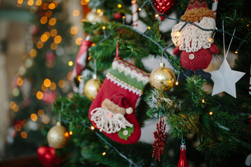 close up shot of a decorative red sock that hangs on a green Christmas tree