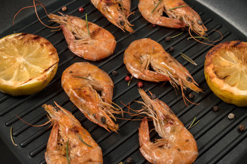 Grilled shrimp on a grill frying pan with lemon, paprika, spices and herbs.
