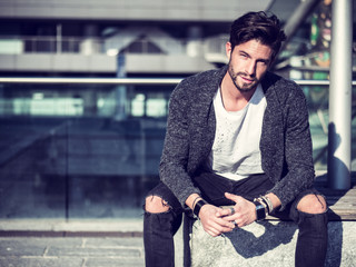 One handsome man in urban setting in European city, sitting