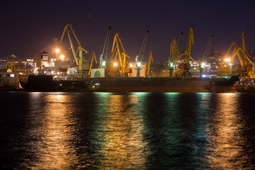 Fototapeta na wymiar Vessel dry cargo on loading, unloading in port at night time. Bulker in port.
