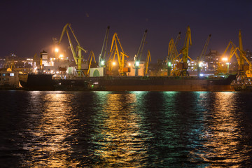 Fototapeta premium Vessel dry cargo on loading, unloading in port at night time. Bulker in port.