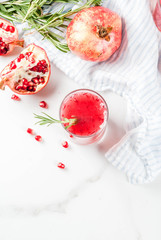 Homemade boozy alcoholic pomegranate cocktail with rosemary and vodka, white marble background, copy space top view