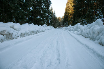 Winter road in the forest. Thoroughfare covered with deep snow in the winter forest in the mountains.