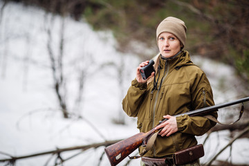 female hunter ready to hunt, holding laser finder in forest. hunting and people concept