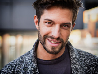 Obraz premium One handsome young man in urban setting in European city, standing, smiling and looking at camera