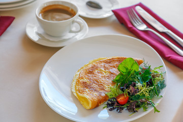 A breakfast with some omlette, greens and coffee