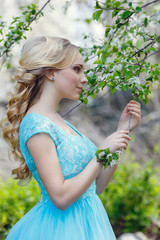 Beautiful blonde young woman wearing fashionable clothes walking in the spring park.