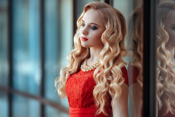 Naklejka premium portrait of stylish beautiful girl wearing short red dress posing or walking at the street