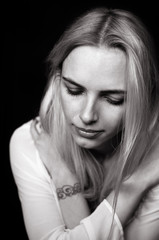 Beautiful girl cries, demonstrating her sadness and emotions. Black and white photo depicting a blonde model is upset in depression.