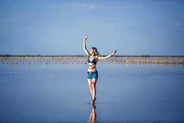 Sexy woman on the sand beside a lake with a pink water
