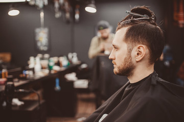 Barbershop. man in a hairdresser is preparing barber to cut hair with hairpin clips.
