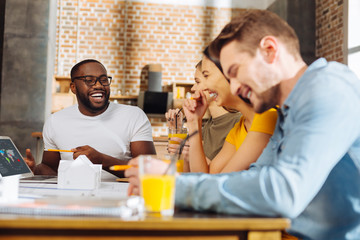 Group discussion. Four thoughtful cheerful optimistic  students laughing while working  and preparing project 