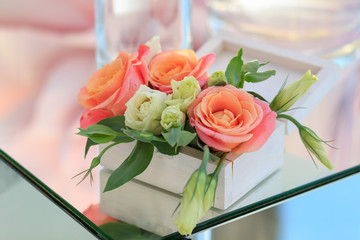 white wooden box with fresh flowers stands on a mirrored table