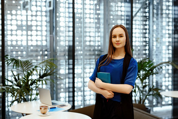 The young business woman with the daily log in hands against the background of office.