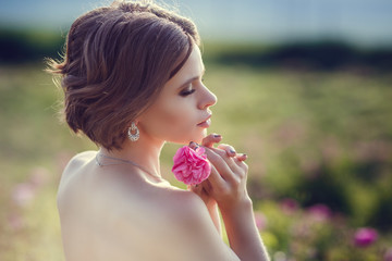 Beautiful young woman in a blooming rose garden