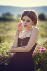 Fototapeta na wymiar Beautiful young woman in a blooming rose garden