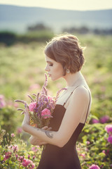 Beautiful young woman in a blooming rose garden