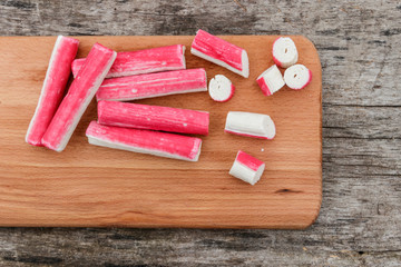 Crab sticks on cutting board on rustic wooden table