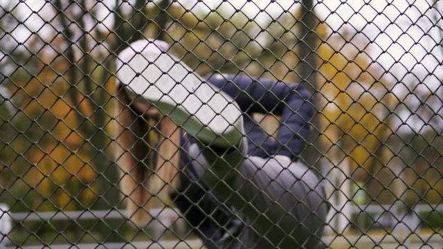 Hipster woman looks over the fence and kicks. Slow Mo