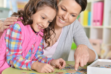 Mother with little daughter collecting  puzzle