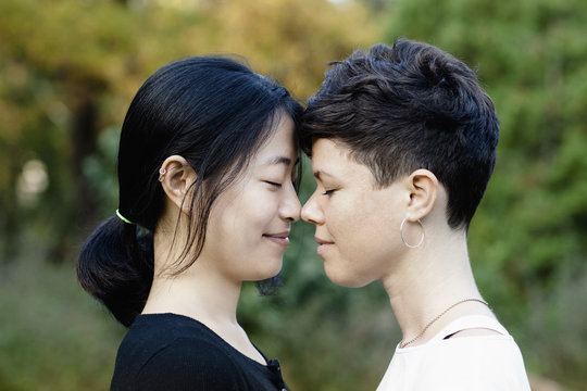 Close-up of smiling lesbian couple standing face to face at park