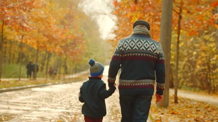 Little boy and his grandfather are having a walk in the autumn park - Powered by Adobe