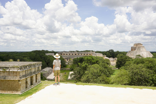 Full length of boy looking at pyramids against cloudy sky, Uxmal, Yucatan, Mexico