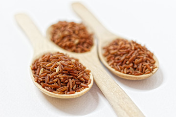 Thai Black or dark brown raw rice in a wooden spoon for a healthy diet. High fiber, vitamin, carbohydrate, minerals, and nutrition for healthy people. on the white background, isolate.
